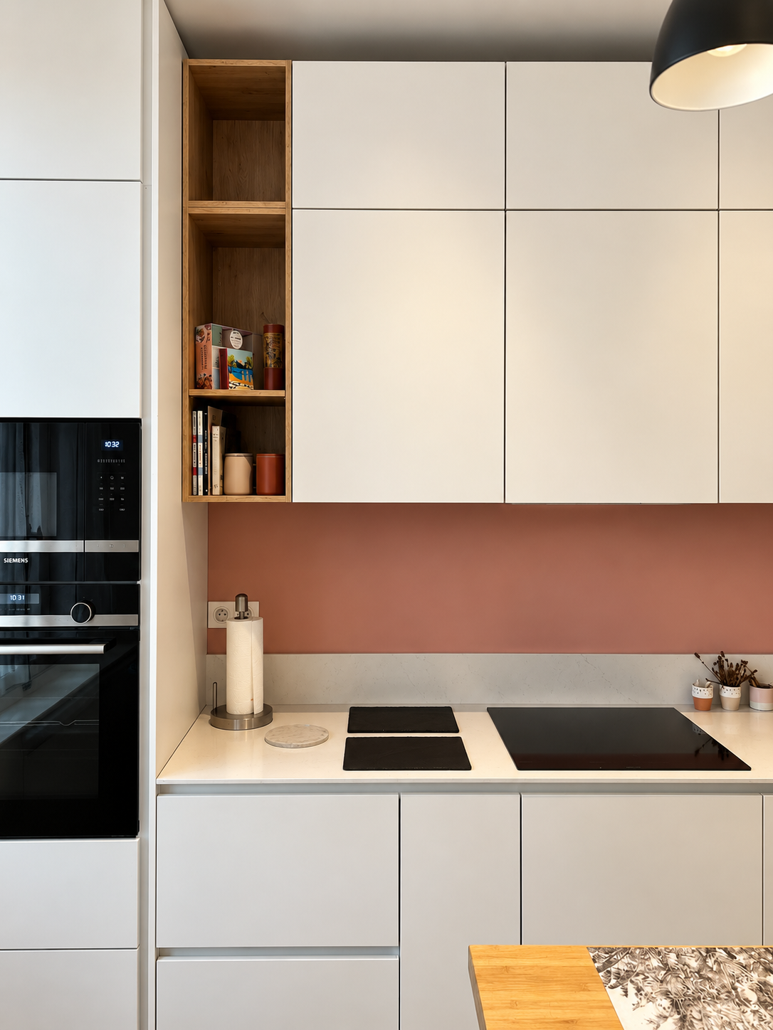 Cuisine blanche sur mesure avec crédence rose poudré, plan de travail clair et rangements en bois